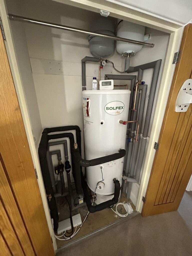 A hot water cylinder installed as part of an air source heat pump system.